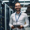 IT-Techniker mit Tablet im modernen Rechenzentrum zwischen beleuchteten Server-Racks