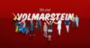 Menschen aus verschiedenen Berufsgruppen vor rotem Hintergrund mit dem Slogan ‚Wir sind VOLMARSTEIN‘ – Symbolbild für Vielfalt und Zusammenhalt im Evangelischen Stift Volmarstein.