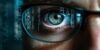 Nahaufnahme eines Auges hinter einer Brille mit Spiegelung von digitalen Daten und Codezeilen, symbolisiert Cybersecurity und Datenanalyse.