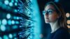 Person betrachtet eine große digitale Anzeige mit leuchtenden blauen Daten und Codezeilen in einer dunklen Umgebung.