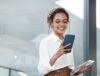 Digitale Arbeitsumgebung: Person nutzt Smartphone im Büro und hält zusätzlich ein Tablet
