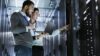 Zwei IT-Experten inspizieren Serverracks im Rechenzentrum, mit Laptop in der Hand.“